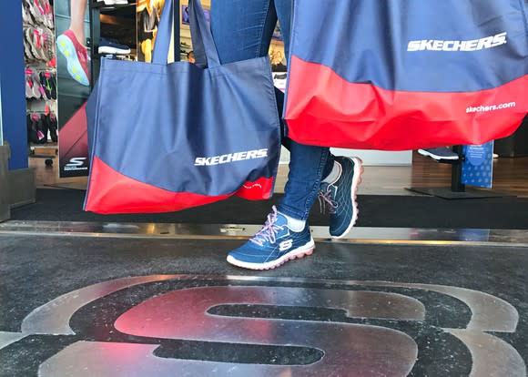 Customer carrying two Skechers bags out of the store, while wearing Skechers shoes.