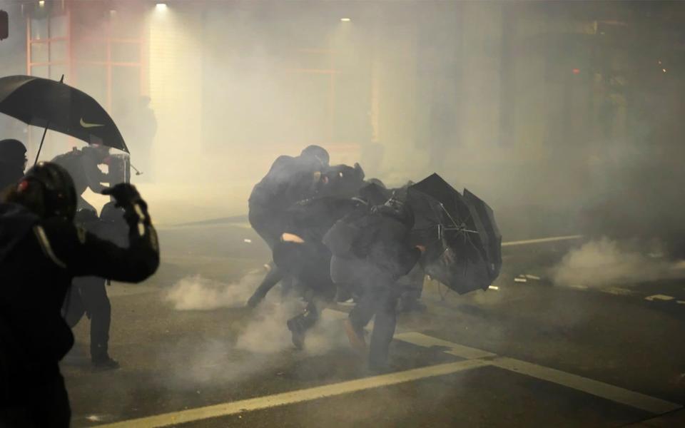 A group of protesters dressed in black use umbrellas to shield themselves - Assfault Pirates via AP