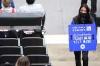 An usher holds a sign reminding fans about COVID-19 precautions, during the first half of an NBA basketball game between the Boston Celtics and the Chicago Bulls in Chicago, Friday, May 7, 2021. (AP Photo/Nam Y. Huh)