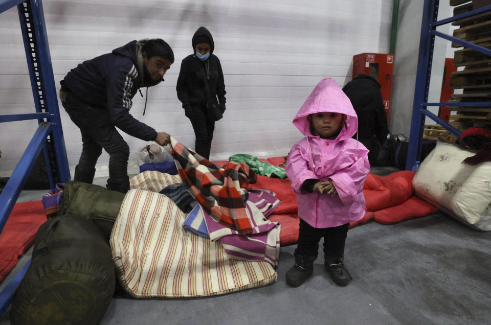 Migrants settle for the night in the logistics center in the checkpoint "Kuznitsa" at the Belarus-Poland border near Grodno, Belarus, on Tuesday, Nov. 16, 2021. Polish border forces say they were attacked with stones by migrants at the border with Belarus and responded with a water cannon. The Border Guard agency posted video on Twitter showing the water cannon being directed across the border at a group of migrants in a makeshift camp. (Maxim Guchek/BelTA via AP)