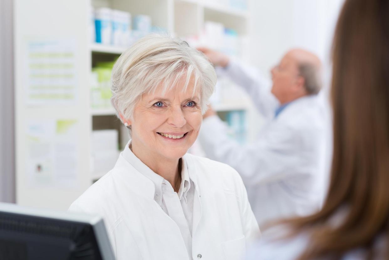 female pharmacist with a warm welcoming smile helping a patient in the pharmacy