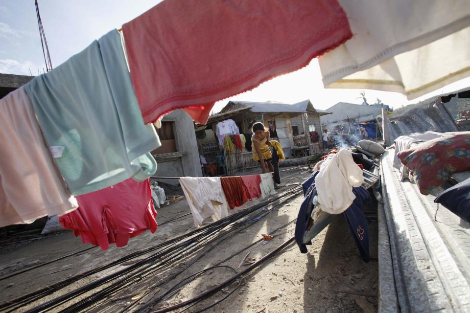 Residents hang clothes on wires from a fallen electric post after super Typhoon Haiyan hit Daanbantayan town