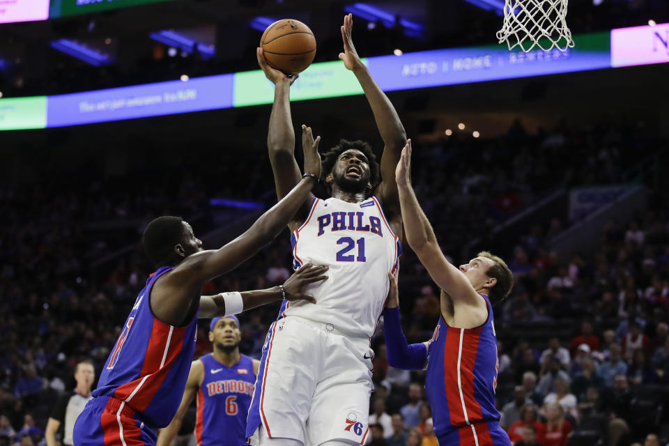 Philadelphia 76ers' Joel Embiid (21) shoots as Detroit Pistons' Tony Snell, left, and Luke Kennard defend during the second half of an NBA preseason basketball game Tuesday, Oct. 15, 2019, in Philadelphia. The 76ers won 106-86. (AP Photo/Matt Rourke)