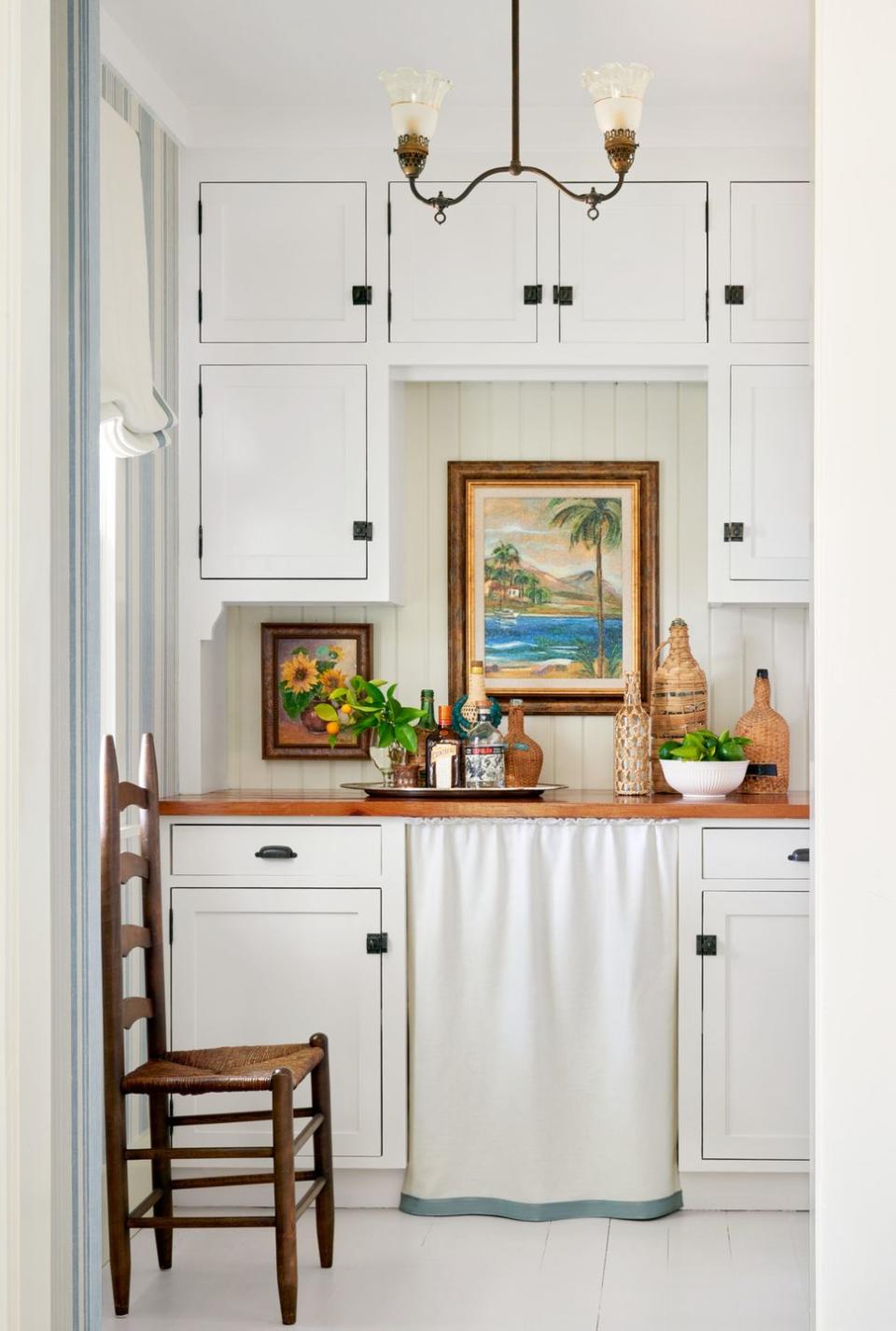 white wet bar with skirted sink, white painted floors, ladder back chair nearby