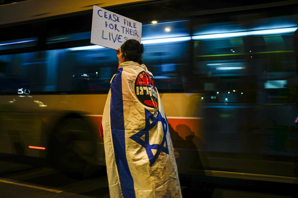 A demonstrator wrapped in the Israeli flag holds a sign during a rally calling for the release of the hostages held in the Gaza Strip by the Hamas militant group, in Tel Aviv, Israel, Saturday, March 9, 2024. With each passing day, the relatives of hostages in Gaza face a deepening despair. (AP Photo/Ariel Schalit)