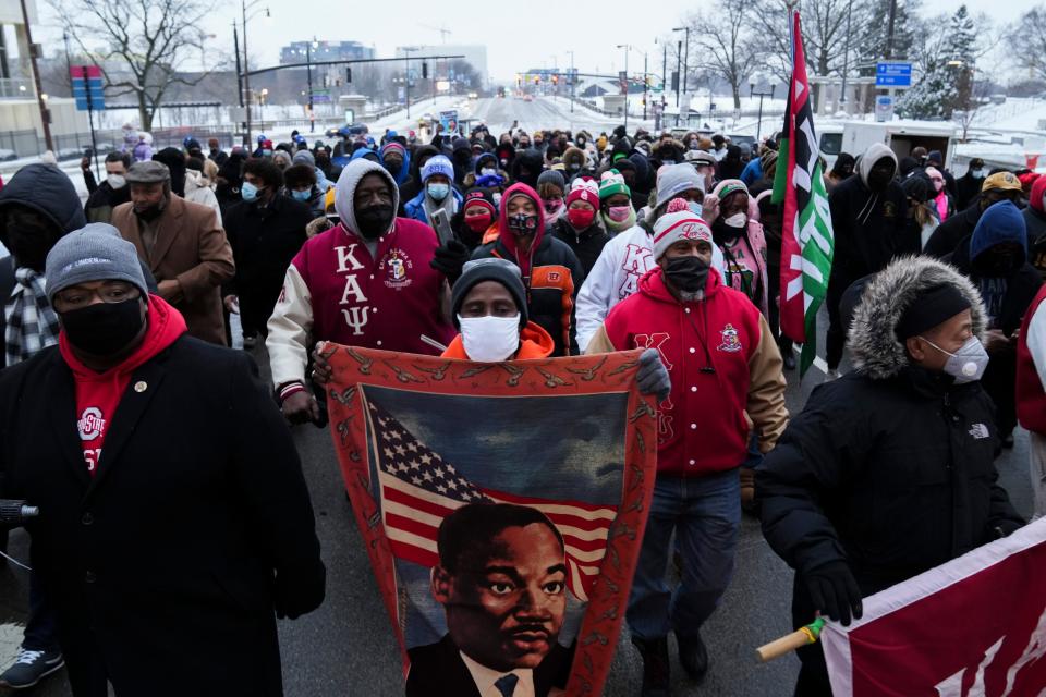 Tyrone Little, center, of the West Side, carries a blanket featuring the image of Martin Luther King Jr. as he walks during a MLK March in Downtown on Jan. 17, 2022. The march, organized by the City of Columbus, featured speakers and a march through the streets of downtown to commemorate the life and legacy of King.