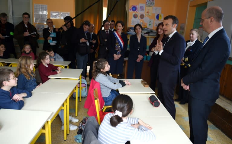 French President Emmanuel Macron is watched by French minister of National Education, Jean-Michel Blanquer as he interacts with children during a visit to the primary school of Rilly-sur-Vienne in central France