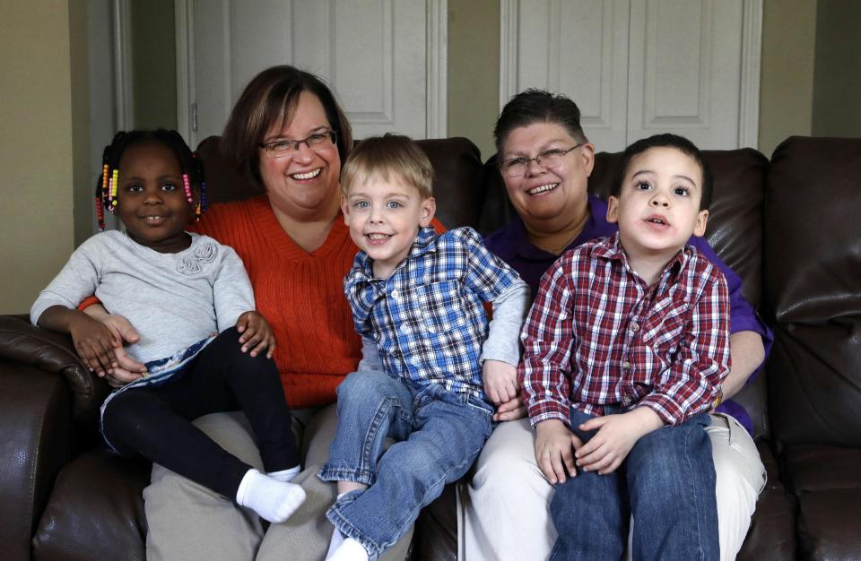 FILE- In a March 5, 2013, file photo, April DeBoer, second from left, sits with her adopted daughter Ryanne, left, 3, and Jayne Rowse, fourth from left, and her adopted sons Jacob, 3, middle, and Nolan, 4, right, at their home in Hazel Park, Mich. On Tuesday, Feb. 25, 2014, U.S. District Judge Bernard Friedman is scheduled to open a trial on the women’s challenge to Michigan’s ban on gay marriage and joint adoptions by same-sex couples. (AP Photo/Paul Sancya, File)