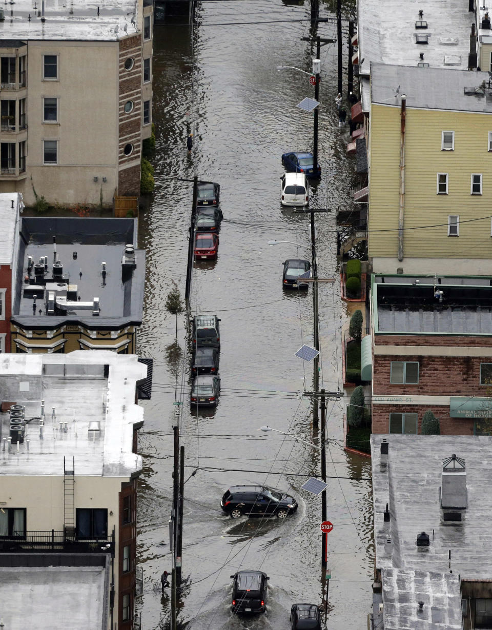 A vehicle drives on a flooded street in the wake of superstorm Sandy on Tuesday, Oct. 30, 2012, in Hoboken, N.J. Sandy, the storm that made landfall Monday, caused multiple fatalities, halted mass transit and cut power to more than 6 million homes and businesses. (AP Photo/Mike Groll)