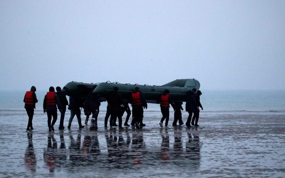 Migrants carry an inflatable dinghy to sea in northern France as they attempt to cross the English Channel - GONZALO FUENTES /REUTERS