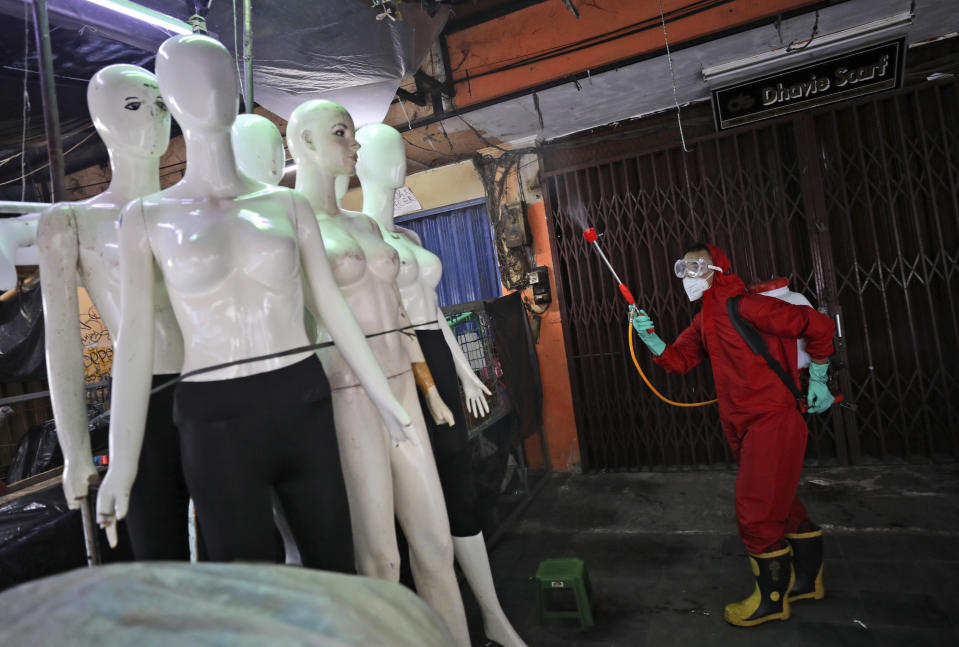 A fireman sprays disinfectant at mannequins as a precaution against coronavirus outbreak, at Tanah Abang textile market in Jakarta, Indonesia, Thursday, June 4, 2020. Authorities in Indonesia's capital will ease a partial lockdown as the world's fourth most populous nation braces to gradually reopen its economy. (AP Photo/Dita Alangkara)