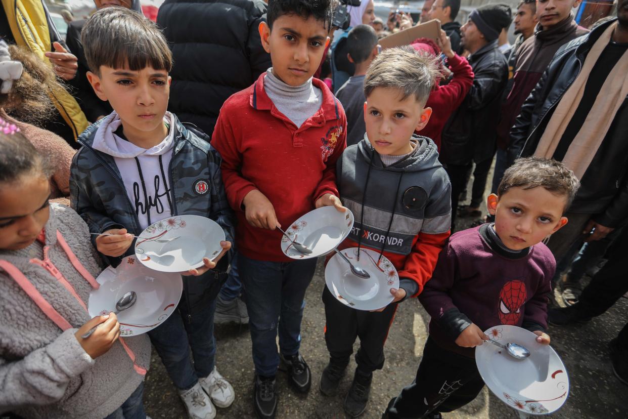 Palestinian children carry empty bowls during a march demanding an end to the war on March 6, 2024, in Rafah, Gaza.