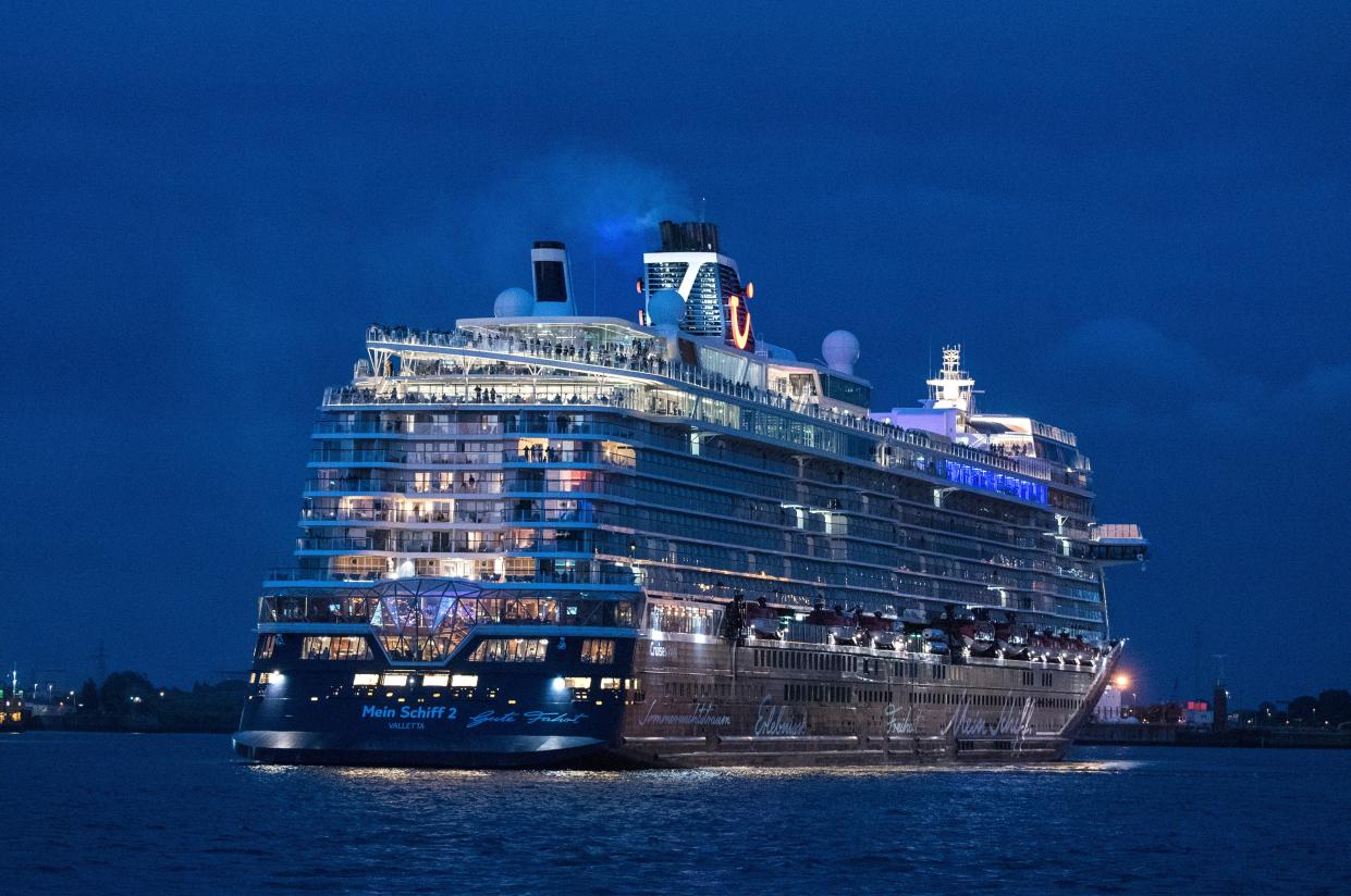 Passengers stand on board the Tui cruise ship 'Mein Schiff 2' during the departure from the port for a three-day trip on the North Sea in Hamburg, Germany, Friday, July 24, 2020. The cruise ship has set sail for the first time since the industry was shut down due to the coronavirus pandemic, with strict precautions to keep passengers and crew as safe as possible. Passengers will spend the weekend at sea with no land stops before returning to Germany on Monday.