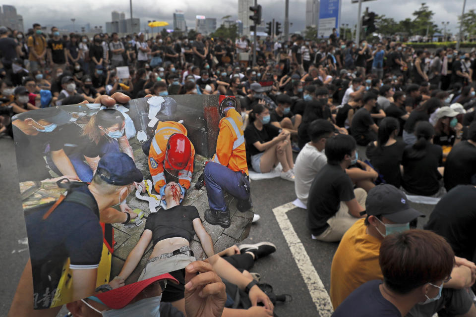 In this Monday, June 17, 2019, photo, a protester holds a photo of an injured protester after crashing with policemen from the previous rally, as they gather near the Legislative Council to continue protest against the unpopular extradition bill in Hong Kong. All but a handful of protesters in Hong Kong have gone home, but the crisis that brought nearly 2 million into the streets to oppose the extradition bill is far from over. (AP Photo/Kin Cheung)