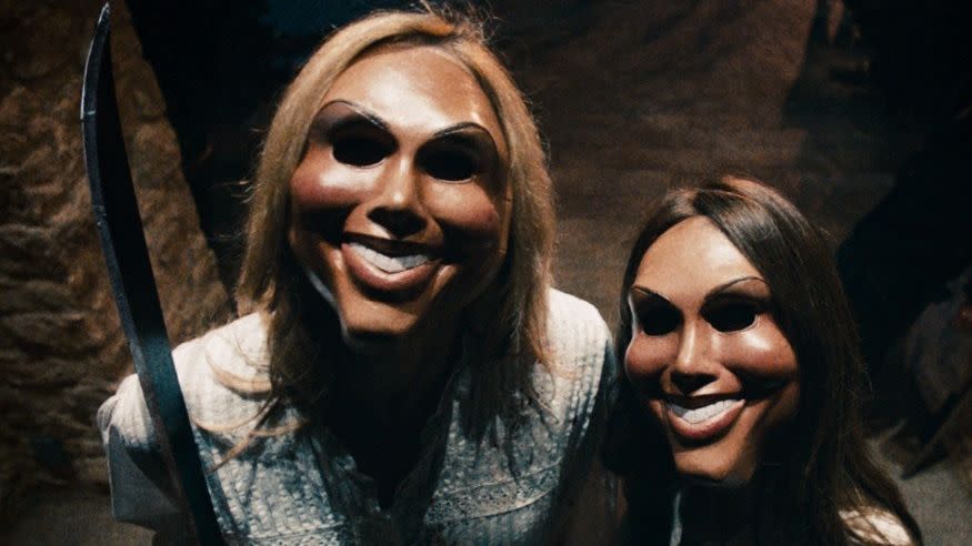two people in masks ring a doorbell in a scene from the purge, a good housekeeping pick for best halloween movies