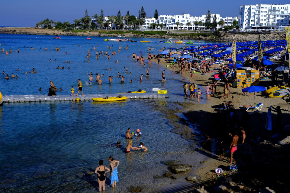 Swimmers cool off from the mid-summer heat in the clear east Mediterranean waters of Cyprus' Fig Tree Bay in the coastal resort of Protaras near Ayia Napa on Saturday, July 18 2020. Tourism-reliant Cyprus projects that this year, it will receive less than a quarter of the record 3.9 million holiday makers it got in 2019 because of the global coronavirus pandemic. (AP Photo/Petros Karadjias)