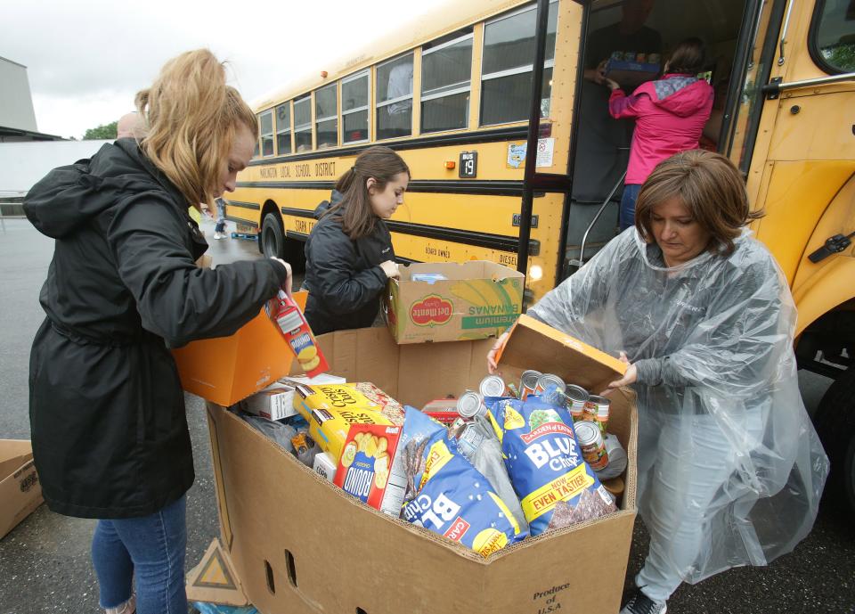 Mattie Vanderhorst, left, Nicole Yoder, center, and Lisa Frank, all with Surgere, load food from a Marlington Local school bus.