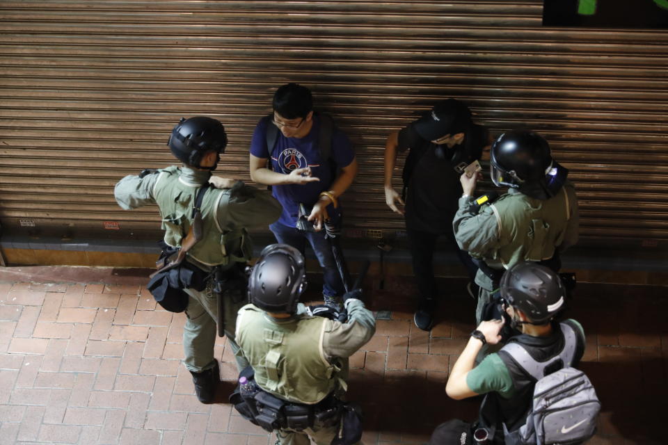 Police check the identity of commuters in Hong Kong, Sunday, Sept. 29, 2019. Riot police fired tear gas Sunday after a large crowd of protesters at a Hong Kong shopping district ignored warnings to disperse in a second straight day of clashes, sparking fears of more violence ahead of China's National Day. (AP Photo/Vincent Thian)