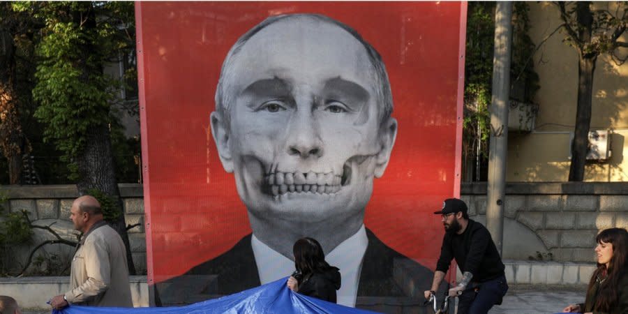Protesters against Russia's war in Ukraine pass by a picture of dictator Vladimir Putin at an anti-war exhibition near the Russian embassy in Bucharest, Romania. April 30, 2022