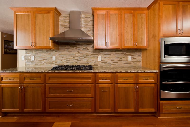 Kitchen with ambered wood cabinets and brown mosaic tile backsplash