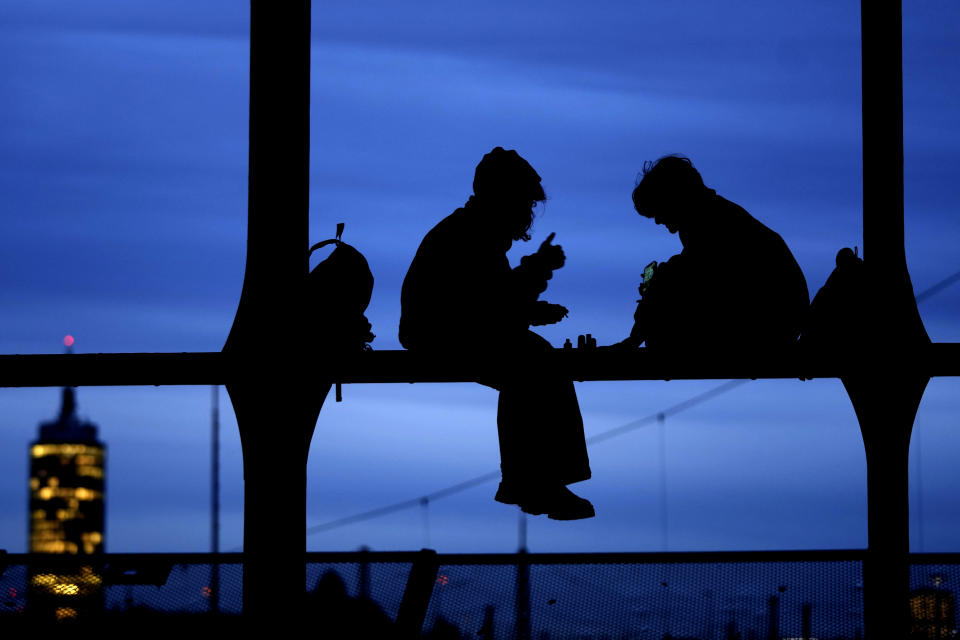 Two children sit on a bridge Tuesday evening in Munich, Germany, Tuesday, Jan. 23, 2024. (AP Photo/Matthias Schrader)