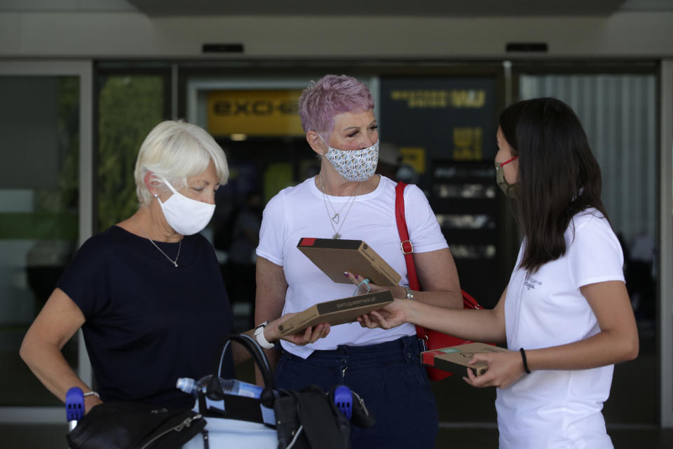 A Algarve tourism authority worker hands out COVID-19 welcome kits containing masks and disinfectant to passengers from the United Kingdom arriving at Faro airport, outside Faro, in Portugal's southern Algarve region, Monday, May 17, 2021. British vacationers began arriving in large numbers in southern Portugal on Monday for the first time in more than a year, after governments in the two countries eased their COVID-19 pandemic travel restrictions. (AP Photo/Ana Brigida)