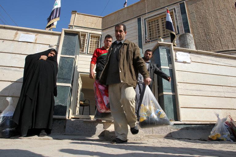 Iraqis who fled Fallujah with their families collect aid supplies distributed by insurgent group Asaib Ahl Al-Haq on January 9, 2014 in Karbala