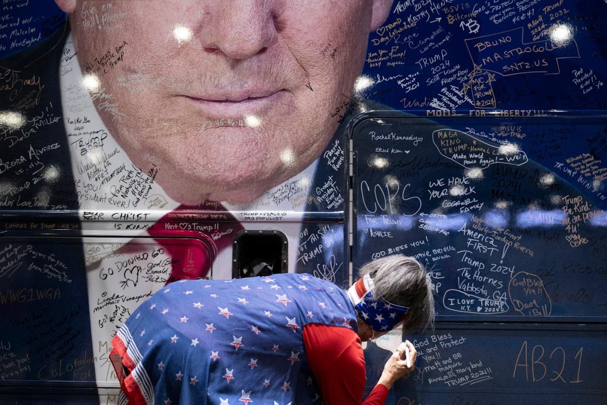 A person signs a bus wrapped with an image of former President Donald Trump during the Conservative Political Action Conference on Feb. 22, 2024. <a href="https://www.gettyimages.com/detail/news-photo/person-signs-a-bus-wrapped-with-an-image-of-former-us-news-photo/2023789392?adppopup=true" rel="nofollow noopener" target="_blank" data-ylk="slk:Brendan Smialowski/AFP via Getty Images;elm:context_link;itc:0;sec:content-canvas" class="link ">Brendan Smialowski/AFP via Getty Images</a>