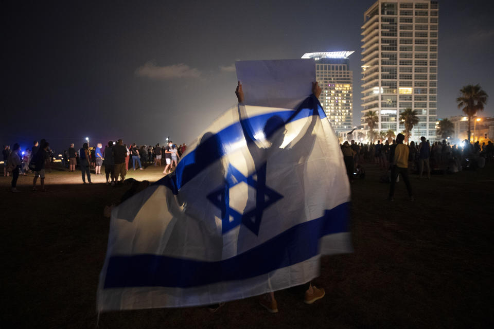 Protesters wave the Israeli national flag during a protest against Israel's Prime Minister Benjamin Netanyahu in Tel Aviv, Israel, Saturday, July 25, 2020. Protesters demanded that the embattled Israeli leader resign as he faces a trial on corruption charges and grapples with a deepening coronavirus crisis. (AP Photo/Oded Balilty)