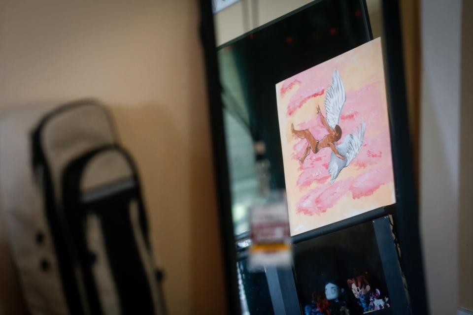 Seen through a mirror, a painting depicting gender dysphoria sits on Romeo's television stand on Thursday, April 20, 2023.