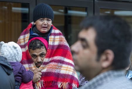 A young migrant cries while waiting with his father outside the foreign office in Brussels, Belgium, September 9, 2015.