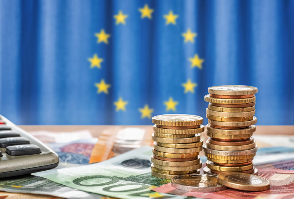 Banknotes and coins in front of the flag of the European Union