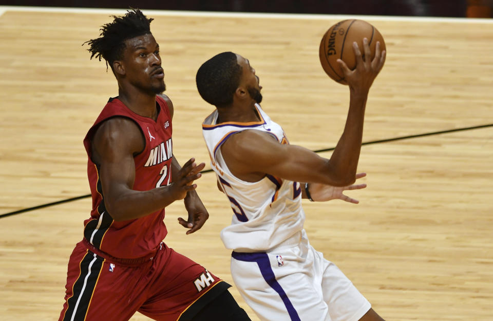 Miami Heat forward Jimmy Butler (22) trails Phoenix Suns forward Mikal Bridges (25), who goes to the basket during the second half of an NBA basketball game Tuesday, March 23, 2021, in Miami. (AP Photo/Jim Rassol)