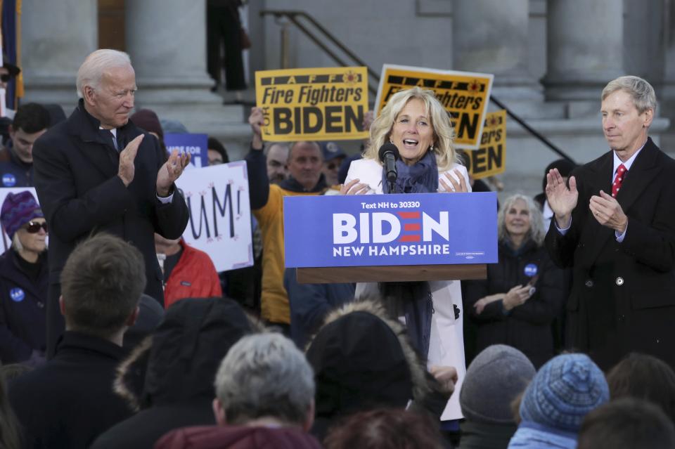 Democratic presidential candidate former Vice President Joe Biden, left, applauds as his wife Jill Biden speaks to supporters outside the New Hampshire State House after he filed to have his name listed on the New Hampshire primary ballot, Friday, Nov. 8, 2019, in Concord, N.H. At right is former Democratic New Hampshire Gov. John Lynch. (AP Photo/Charles Krupa)