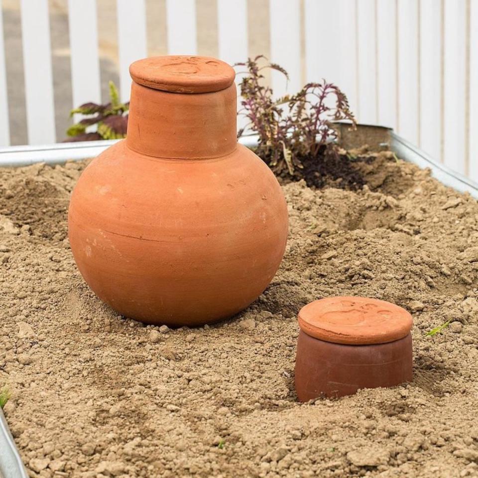 Olla jar in raised bed surrounded by soil