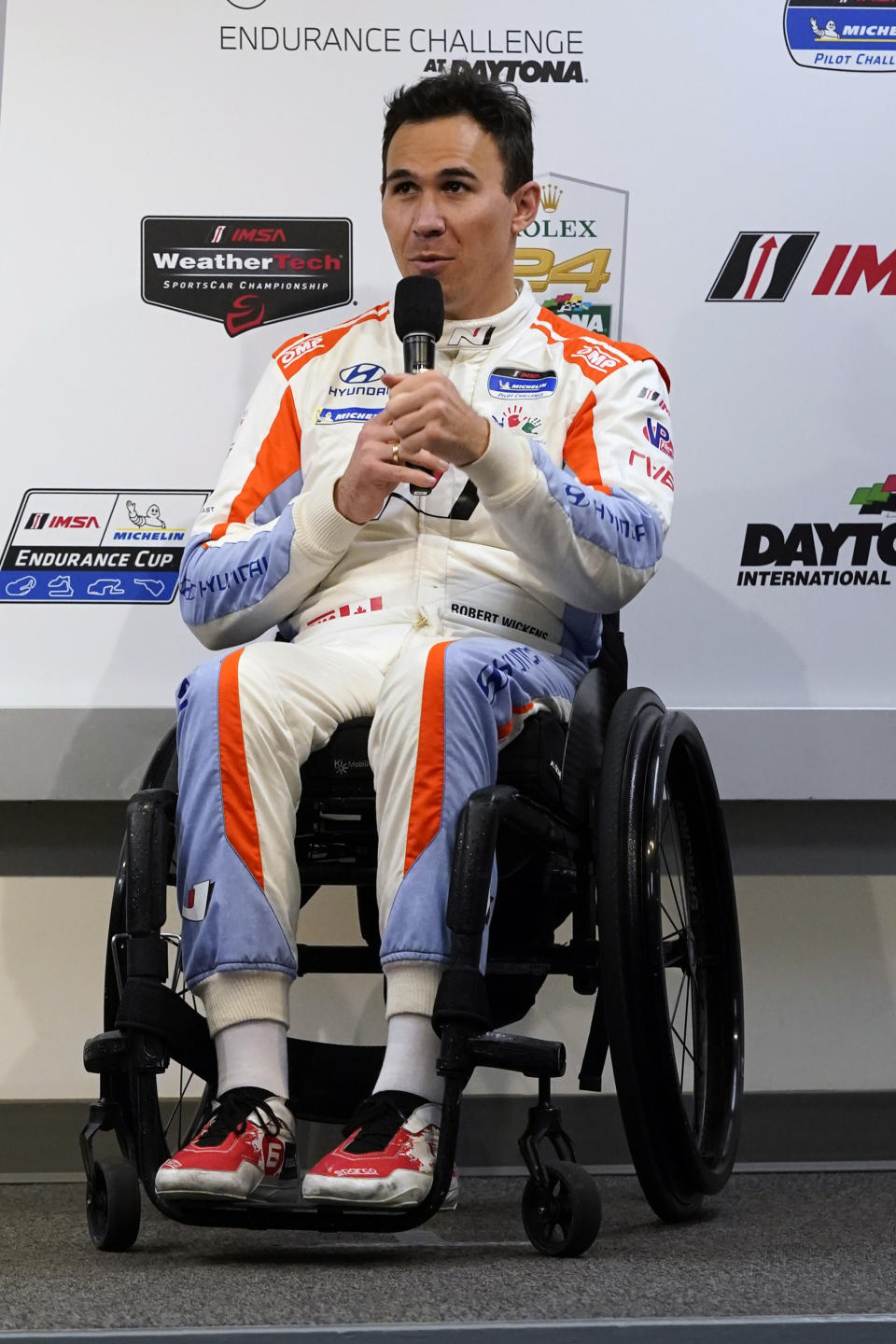 FILE - Robert Wickens answers questions during a new conference for the Rolex 24 hour auto race at Daytona International Speedway, Thursday, Jan. 27, 2022, in Daytona Beach, Fla. Wickens used hand controls last weekend to win his first race since a 2018 spinal cord injury temporarily ended his racing career. Across an ocean, former IndyCar driver Sam Schmidt and motorcycle racer Wayne Rainey also piloted vehicles during the annual Goodwood Festival of Speed in England.(AP Photo/John Raoux, File)