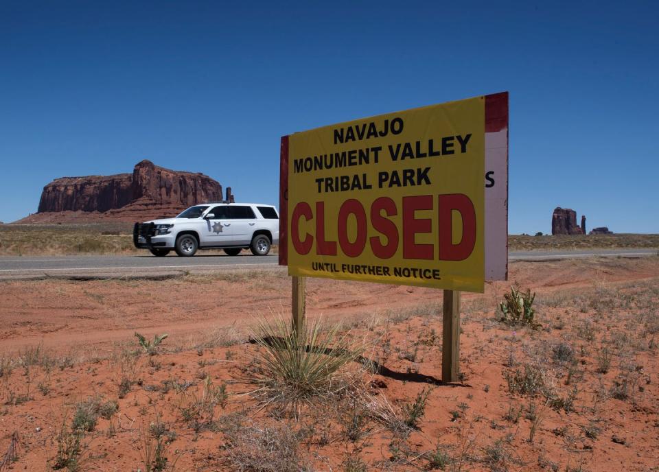 <span class="caption">Monument Valley Tribal Park in Arizona, closed due to the pandemic. Normally, the park would be teeming with tourists this time of year.</span> <span class="attribution"><a class="link " href="https://www.gettyimages.com/detail/news-photo/navajo-park-ranger-drives-outside-the-navajo-nation-managed-news-photo/1214464353?adppopup=true" rel="nofollow noopener" target="_blank" data-ylk="slk:Getty Images / Mark Ralston;elm:context_link;itc:0;sec:content-canvas">Getty Images / Mark Ralston</a></span>