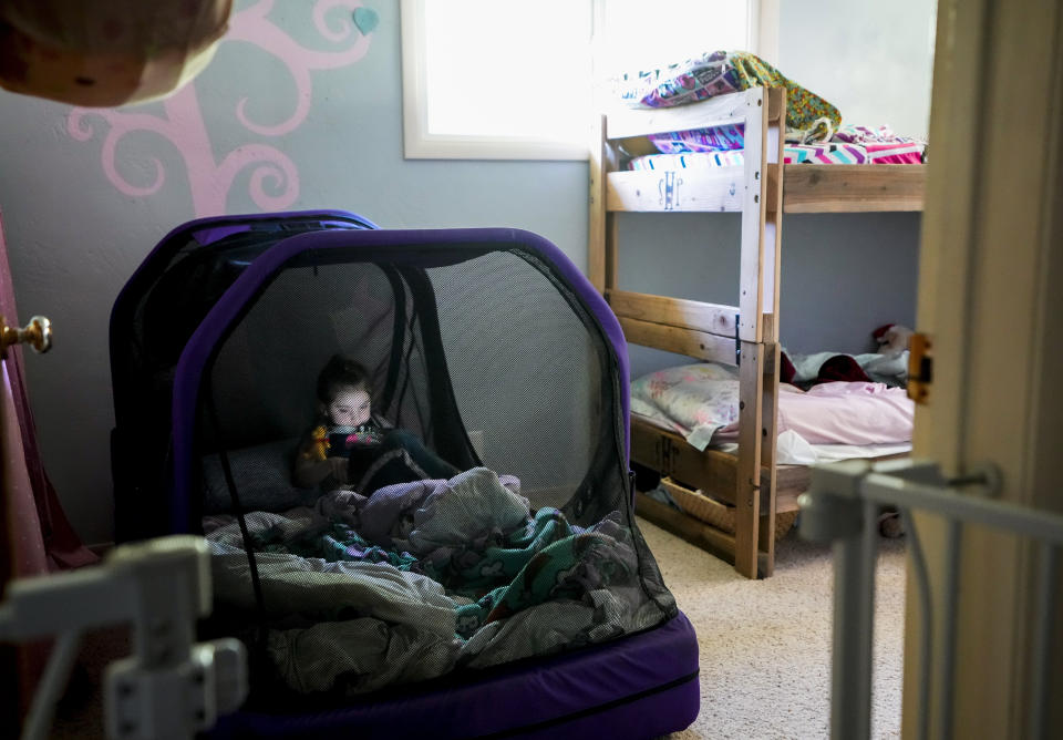 Scarlett Rasmussen, 8, plays on her tablet in her room, Wednesday, May 17, 2023, in Grants Pass, Ore. Chelsea Rasmussen has fought for more than a year for her daughter, Scarlett, to attend full days at Parkside. Scarlett is nonverbal and uses an electronic device and online videos to communicate, but reads at her grade level. She was born with a genetic condition that causes her to have seizures and makes it hard for her to eat and digest food, requiring her to need a resident nurse at school. (AP Photo/Lindsey Wasson)