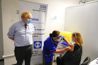 FILE - In this June 21, 2021, file photo, Britain's Prime Minister Boris Johnson, left watches as a woman receive her COVID-19 vaccine, as he visits a vaccination center at the StoneX Stadium, home of the rugby club Saracens, in North London. Britain's Conservative government is hoping a combination of relatively high vaccination rates and common-sense behavior will keep a lid on coronavirus infections this fall and winter and avoid the need for restrictive measures. (AP Photo/Alberto Pezzali, Pool, File)