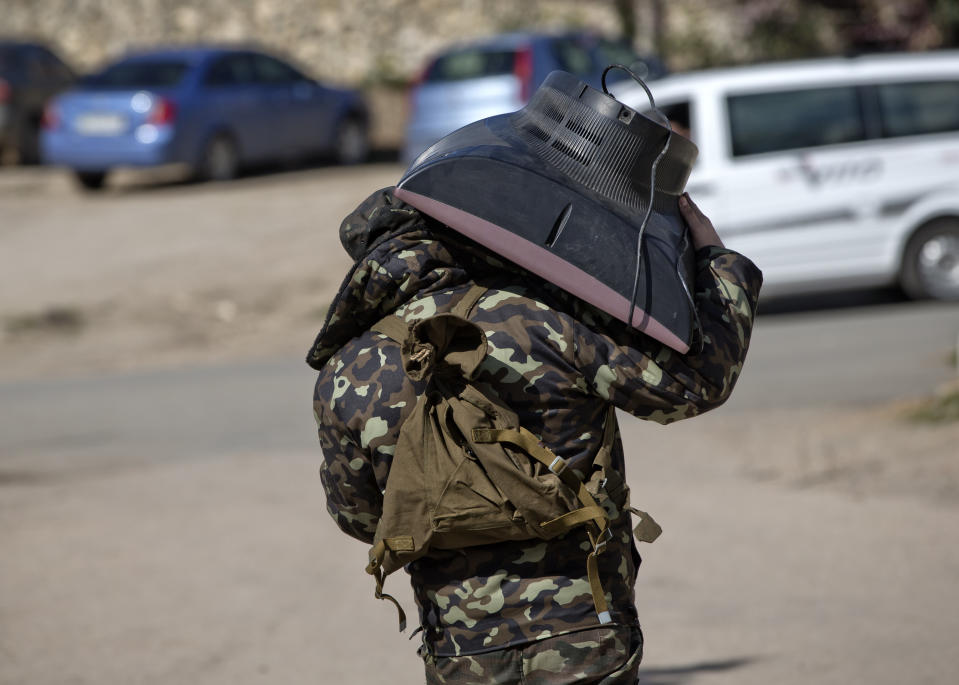 A Ukrainian airman carries a TV set as he leaves the Belbek air base, outside Sevastopol, Crimea, Friday, March 21, 2014. The base commander Col. Yuliy Mamchur said he was asked by the Russian military to turn over the base but is unwilling to do so until he receives orders from the Ukrainian defense ministry. (AP Photo/Vadim Ghirda)
