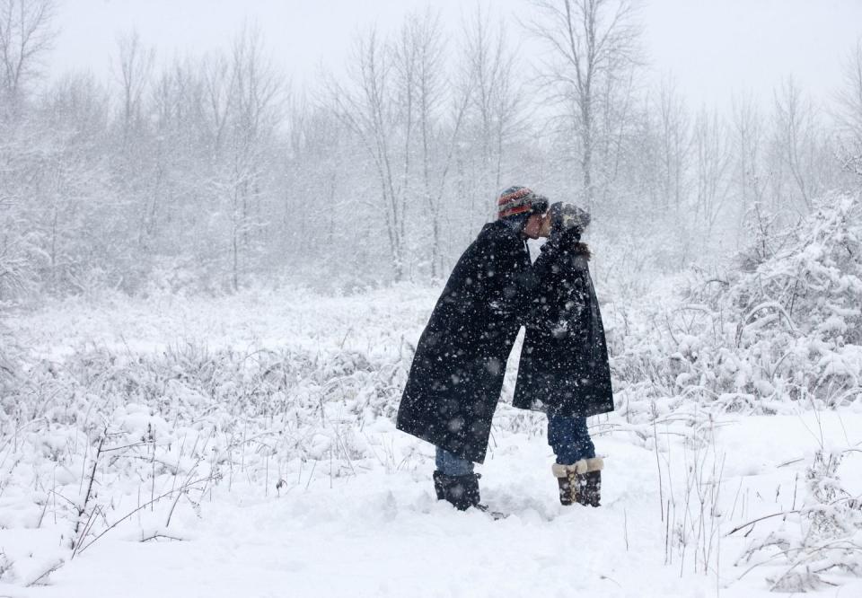 young couple kissing each other in snowfall