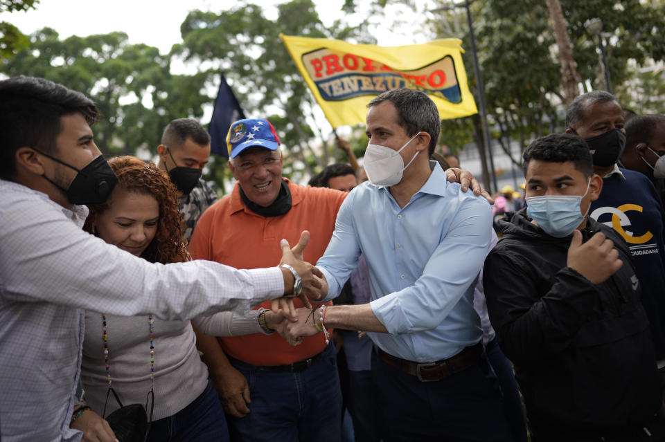 Opposition leader Juan Guaido, center, shakes hands with supporters during a gathering to mark Youth Day, in Caracas, Venezuela, Saturday, Feb. 12, 2022. The annual holiday commemorates the young people who accompanied heroes in the battle for Venezuela's independence. (AP Photo/Ariana Cubillos)