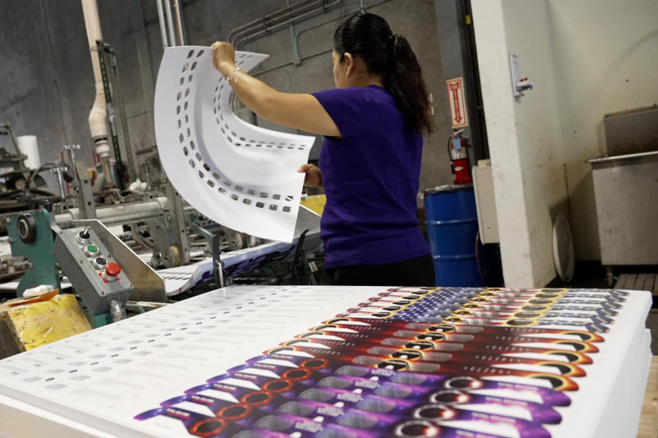 Seventeen pairs of glasses are printed on each large sheet of double laminated paperboard before being fed into a machine in stacks, where a massive hole punch knocks out the center eye holes. (NBC News)