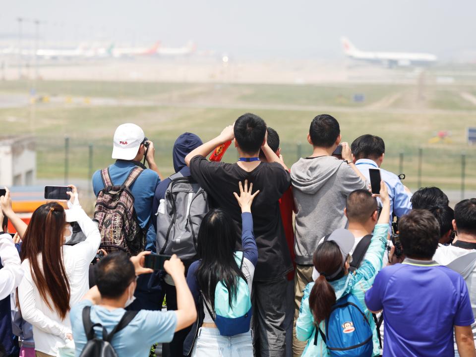 People take photos as China's homegrown C919 passenger jet lands at Beijing Capital International Airport during its maiden commercial flight on May 28, 2023 in Beijing, China.