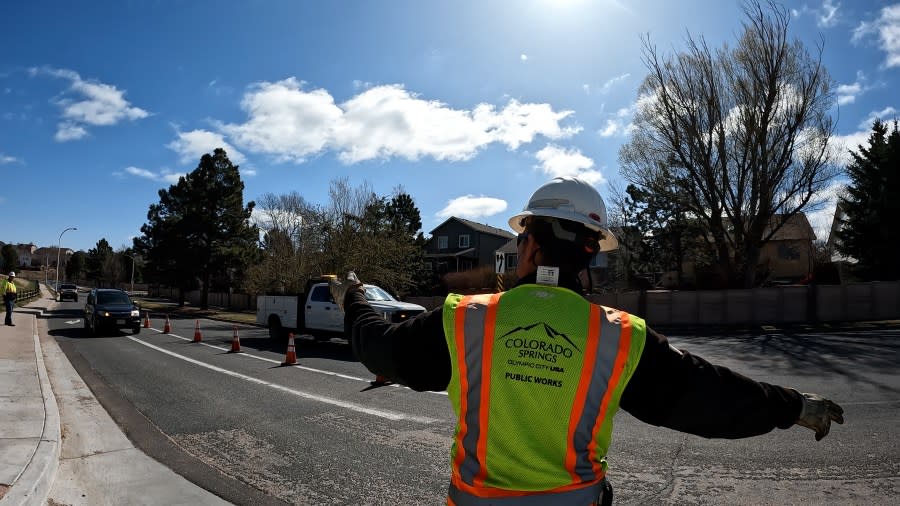 A crew member assisted in directing traffic as the pothole repair was underway, ensuring the safety of everyone involved.