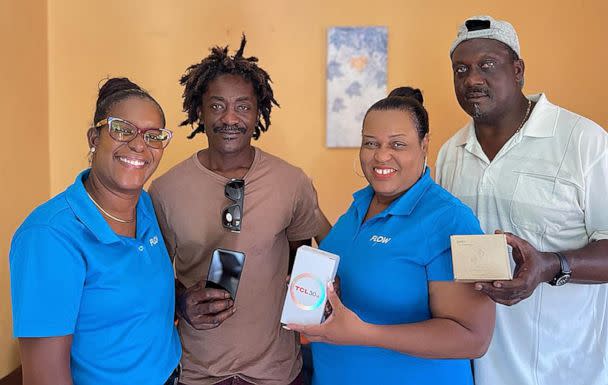 PHOTO: Elvis Francois receives a cellphone from Flow. (Emerline Anselm - CEO, EmoNews)