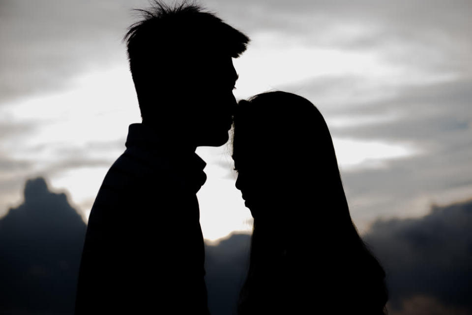 Young couple kissing on the background of a suns