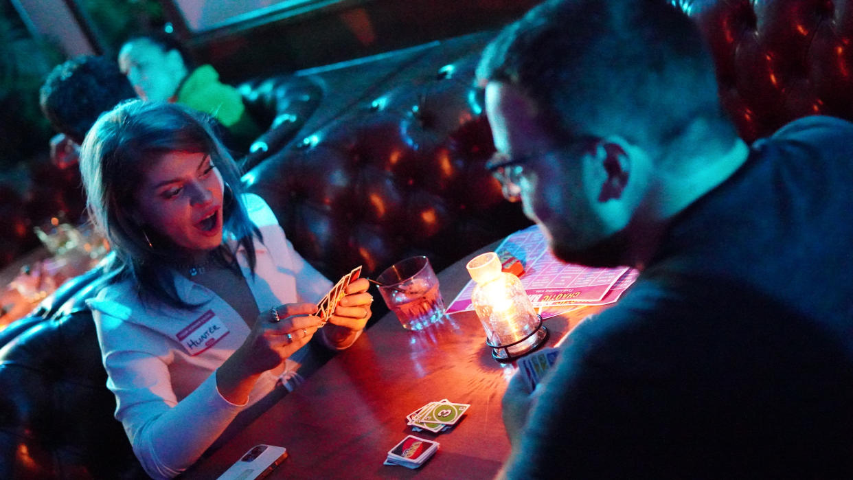 An image of a couple playing the card game Uno at a candlelit table.