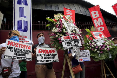 Protesters hold placards calling for a justice for the workers were who killed during a protest in front of a factory gate in Valenzuela city, north of Manila May 15, 2015. REUTERS/Romeo Ranoco
