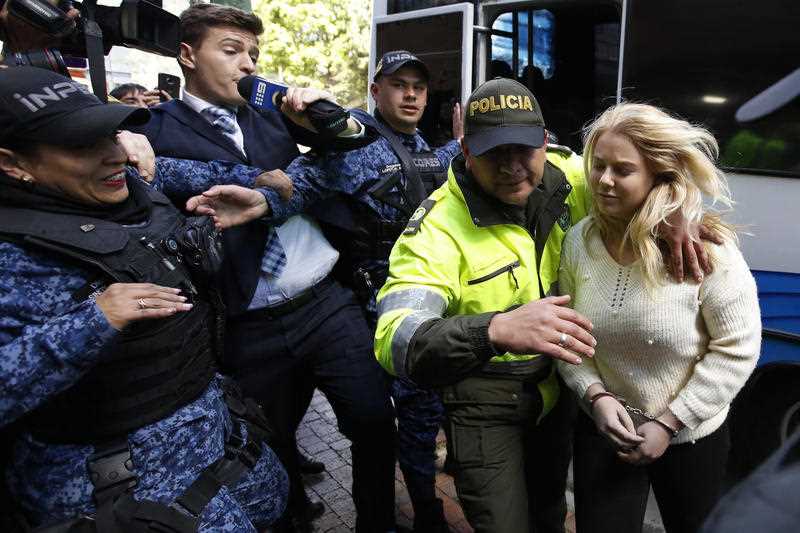 A police officer escorts Australian Cassandra Sainsbury to a court hearing in Bogota, Colombia in 2017.